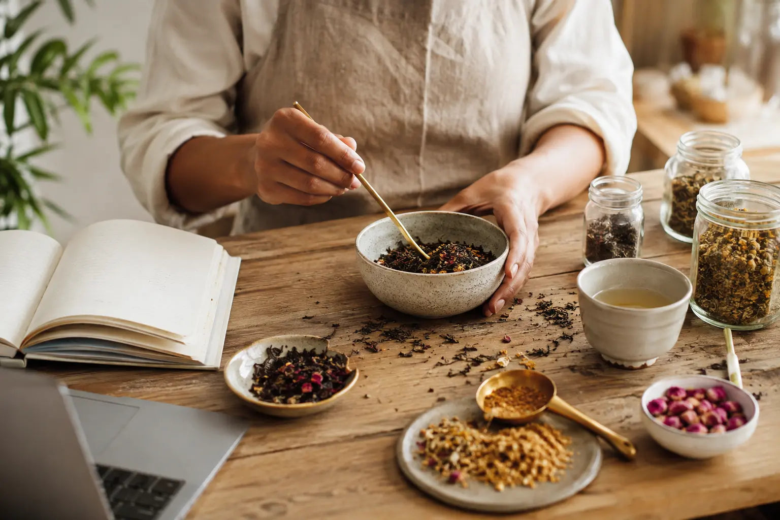Woman tea founder blending herbs and taking notes at her workspace