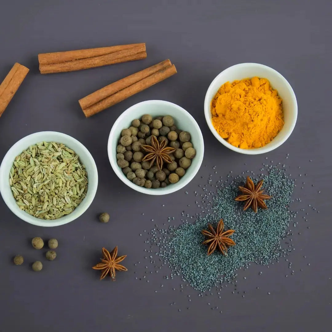 Cinnamon, cloves, black pepper and turmeric arranged beside an Indian-inspired spice tea infusion.