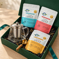 The Tea Ritual Box from the front right with an empty glass kettle, three tea infusions and a gold measuring spoon