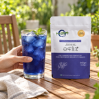 Indigo pouch beside a hand-held glass of blue iced tea with mint on a patio table